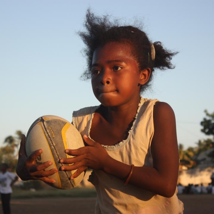 Petite fille tient un ballon de rugby