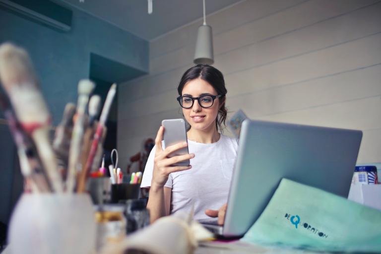 Femme devant son ordinateur, smartphone à la main